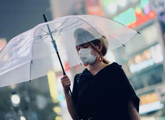 Analysis: How the insurance sector is responding to COVID-19 Woman with protective mask and umbrella